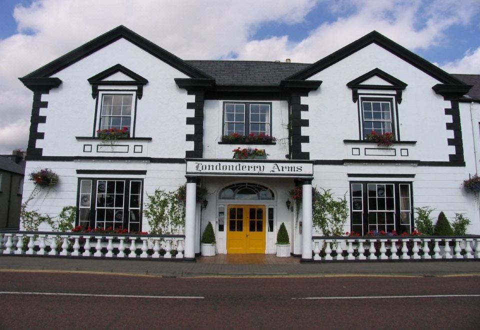 "a white building with black trim and windows , featuring a yellow door and a sign that says "" rannderr arms .""." at Londonderry Arms Hotel