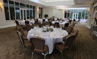 a large dining room filled with round tables and chairs , all set for a formal event at St Andrews Town Hotel