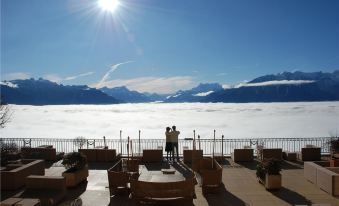 a man and a woman standing on a patio overlooking a large body of water , possibly a lake or the ocean at Le Mirador Resort and Spa