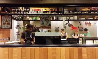 a busy coffee shop with several people working behind the counter , serving drinks and snacks at Go Hotel