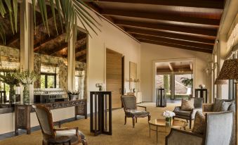 a spacious living room with wooden floors , large windows , and comfortable seating arrangements under a high ceiling at Rosewood Sand Hill