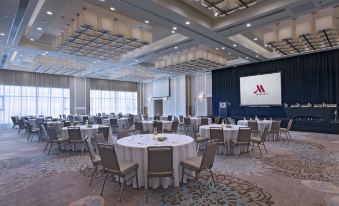 a large , well - decorated conference room with multiple round tables and chairs arranged for a meeting at Guyana Marriott Hotel Georgetown