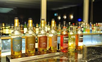 a row of bottles on a bar , including whiskey , wine , and other alcoholic beverages , arranged on a counter at Hotel Aomori