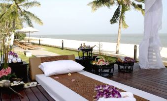 a wooden deck overlooking the ocean , with a bed placed on it and a view of the beach in the distance at Kuiburi Hotel & Resort