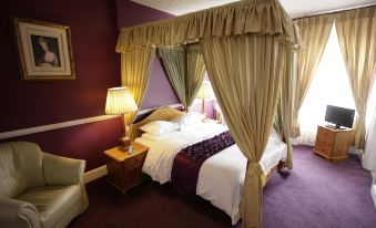a luxurious bedroom with a large bed draped in a canopy , surrounded by purple walls and curtains at The Imperial Hotel