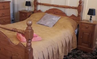 a wooden bed with a beige comforter and two nightstands on either side of the bed at Tudor House