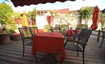 a dining table with a red tablecloth and black chairs is set up outside on a patio at La Cascade