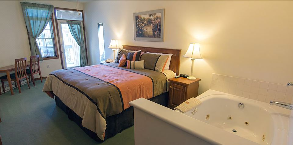 a large bed with a wooden headboard is situated in a room next to a bathroom at Scandinavian Lodge