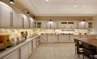 a large , well - equipped kitchen with white cabinets , stainless steel appliances , and a dining table in the center at Hyatt Place Fresno