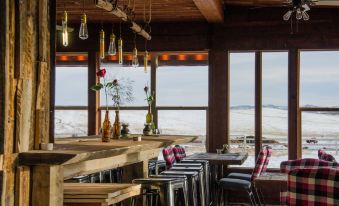 a restaurant with wooden tables and chairs , a bar , and large windows overlooking the ocean at Zion Mountain Ranch
