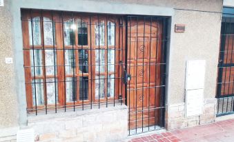 a wooden door with a metal grate on the window is next to a brick wall at Casa Mendoza
