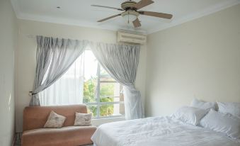a bedroom with a bed , couch , and ceiling fan , as well as a window with curtains at Scenic Views