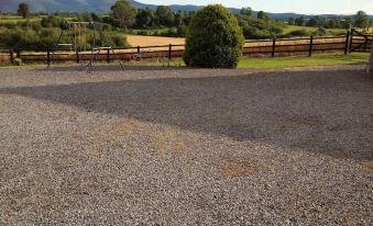 a gravel parking lot with a wooden fence in the foreground and mountains in the background at Brigadoon