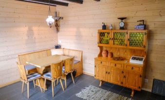 a wooden dining room with a dining table and chairs , a kitchen area , and a wooden cabinet at Chalet Ninette