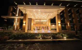 a large hotel entrance lit up at night , with a fountain in front of it at Sarovar Portico, Somnath