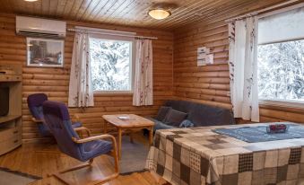 a cozy wooden cabin interior with a dining table , chairs , and a couch in the living area at Kuikka