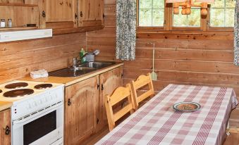 a wooden cabin kitchen with a red and white checkered tablecloth , a stove , and a dining table at Olden