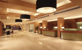a modern hotel lobby with a reception desk , large circular lights , and a staircase leading to the second floor at Novotel Mumbai Juhu Beach