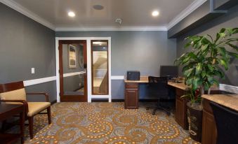 a modern office space with blue walls , wooden doors , and various furniture including a desk , chair , and computer at Best Western Plus Carpinteria Inn