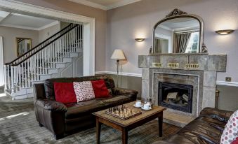 a cozy living room with a fireplace , a leather couch , and a chess board on the coffee table at The Knaresborough Inn - the Inn Collection Group