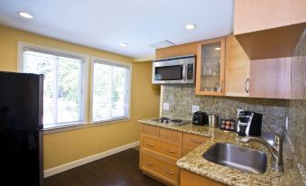a kitchen with yellow walls and wooden cabinets , a sink , oven , microwave , and coffee maker at The Cottages Hotel