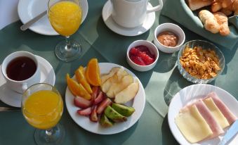 a dining table set with a variety of breakfast foods , including fruits , bread , and juice at Hotel Royal