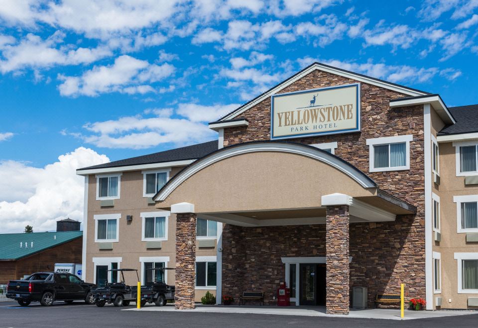 "a building with a sign that says "" yellowstone hotel "" has two cars parked in front of it" at Yellowstone Park Hotel