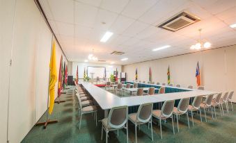 a large conference room with multiple rows of chairs arranged in a semicircle around a long table at Madang Resort