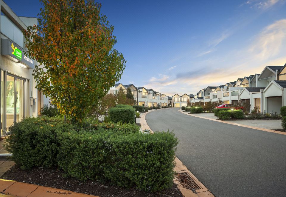 a residential neighborhood with a row of houses and a driveway lined with bushes at Quest Sanctuary Lakes