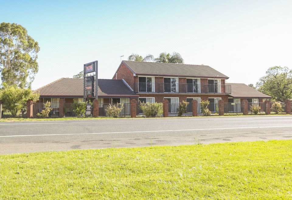 a brick building with a sign on the front , situated in a grassy field near a road at Mildura Riverview Motel