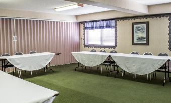 a conference room with several tables and chairs arranged for a meeting , along with a window and curtains at Quality Inn & Suites Newberry