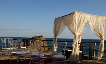 a romantic outdoor setting with a white canopy over the ocean , surrounded by white tables and chairs at Atami Escape Resort