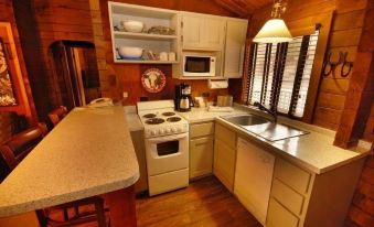 a kitchen with a stove , sink , microwave , and cabinets is shown with wooden walls and shelves at Kohl's Ranch Lodge