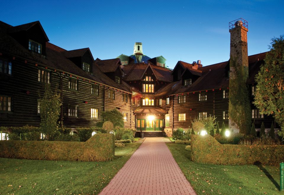 a large wooden mansion with a brick pathway leading up to the entrance , surrounded by greenery at Fairmont le Château Montebello
