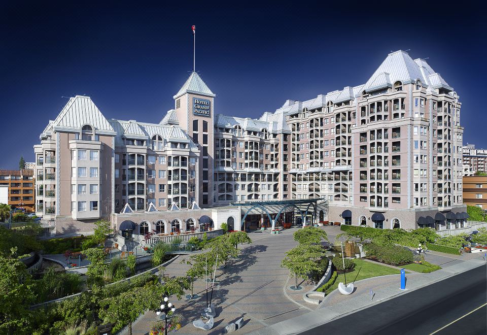 a large hotel building with a clock tower , surrounded by trees and other buildings in the background at Hotel Grand Pacific