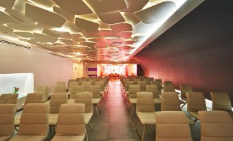 a large , empty conference room with rows of chairs arranged in front of a long table at Hotel Meridional