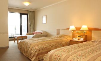 a hotel room with two beds , a couch , and lamps , all arranged neatly in the room at Furano la Terre