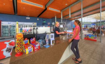 a man and a woman standing at a counter in a sports bar , interacting with each other at Ingenia Holidays Lake Conjola