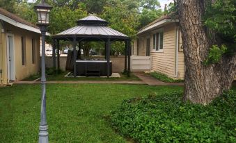 a backyard with a gazebo and a hot tub surrounded by green grass and trees at Fiddler's Inn