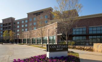 "a large brick building with a sign that reads "" courtyard by marriott "" prominently displayed on the front" at Courtyard Dallas Flower Mound