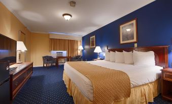 a hotel room with a blue and gold color scheme , featuring a large bed , a desk , and a chair at Best Western White House Inn