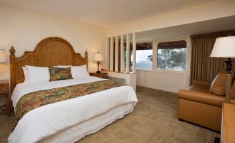 a large bed with a wooden headboard is in a room with a chair and windows at Volcano House