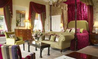 a luxurious bedroom with a large four - poster bed , multiple pieces of furniture , and a chandelier hanging from the ceiling at Ston Easton Park