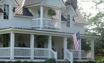 a white two - story house with a flag hanging from the porch and a wooden staircase leading up to the entrance at Seventy-Four Ranch