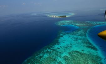aerial view of a large body of water with an island in the distance , surrounded by blue water at Diamonds Athuruga Maldives Resort & SPA
