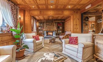 a cozy living room with wooden walls and furniture , including a fireplace , couches , and chairs at Hotel Lo Scoiattolo