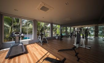a gym with treadmills , stationary bikes , and a weight machine is seen through a large window at Bann Pantai Resort