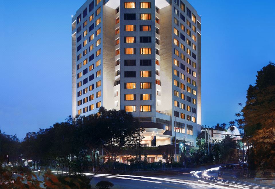 A large building with illuminated lights in the center, situated by water during dusk at Aryaduta Bandung