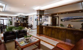 a modern hotel lobby with a wooden reception desk , comfortable seating , and a large painting on the wall at Hotel Don Pepe