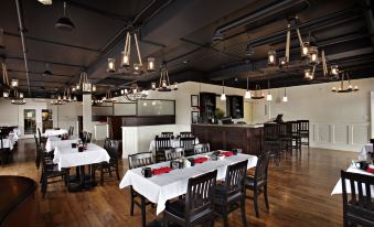 a large dining room with wooden floors , white tablecloths , and black chairs set up for a meal at Sportsman's Inn Resort & Marina